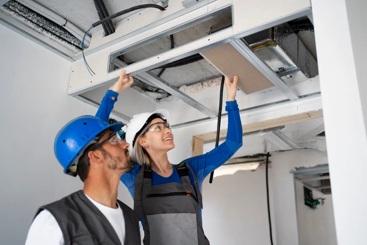 Technicians servicing ceiling ductwork in a commercial space